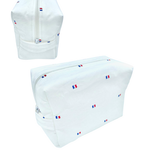 weißer Reisebeutel aus strukturierter Baumwolle mit kleinen französischen Flaggen darauf. Der Reisebeutel hat einen weißen Reißverschluss an der Oberseite und einen weißen Stoffgriff an der Seite. Vorder- und Seitenansicht.
