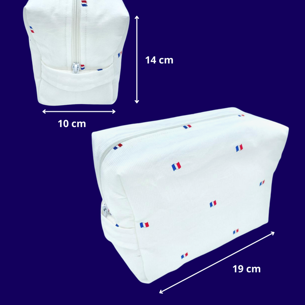Weißer Reisebeutel aus strukturierter Baumwolle mit kleinen französischen Flaggen darauf. Der Reisebeutel hat einen weißen Reißverschluss an der Oberseite und einen weißen Stoffgriff an der Seite. Vorder- und Seitenansicht. Der Beutel ist 19 cm lang, 14cm hoch und 10 cm breit. 