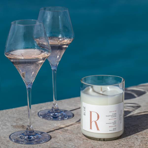 Eine Kerze Rosé steht neben zwei Gläser Rosé mit einem Pool im Hintergrund